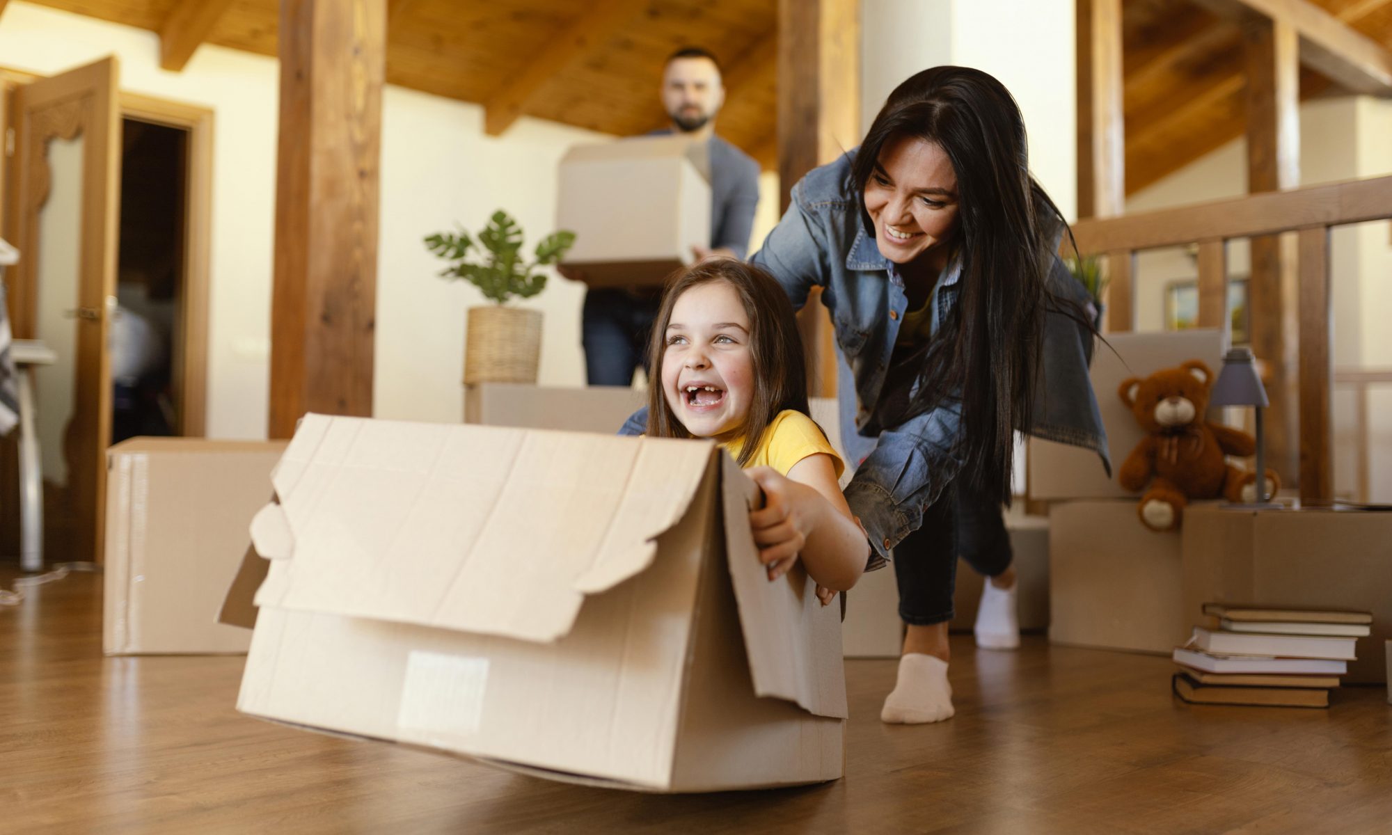 Mother plays with her daughter in a moving box in her newly upgraded home