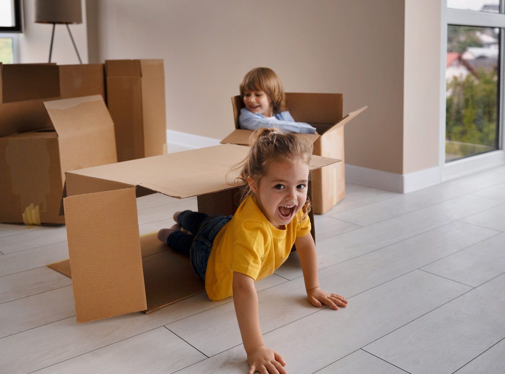 happy kids having fun with boxes after moving home