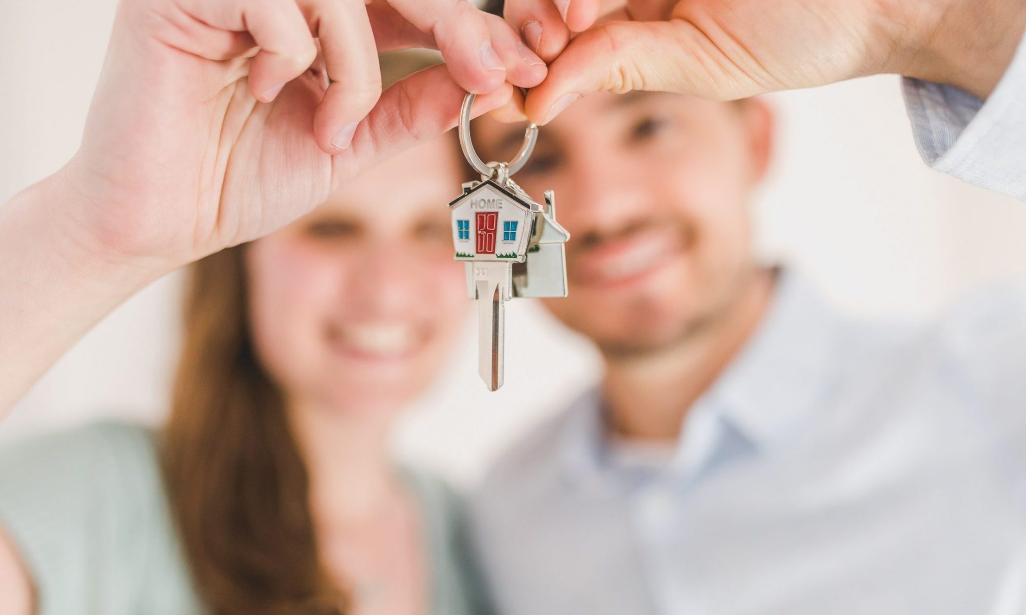 Couple hold up house keys together as they ponder whether to choose auction or private sale when selling their house