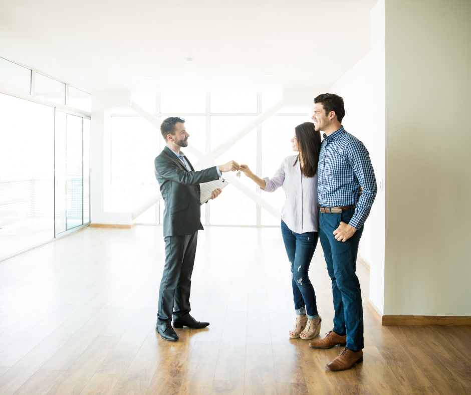 A real estate agent hands the keys to a couple to their new home