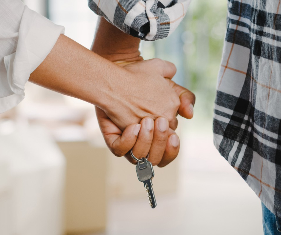 Couple holding hands and holding a key to their new home