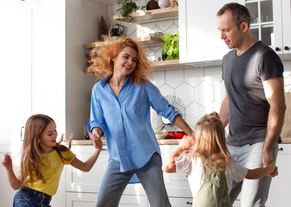 A mum, dad and two daughters dance around their living room